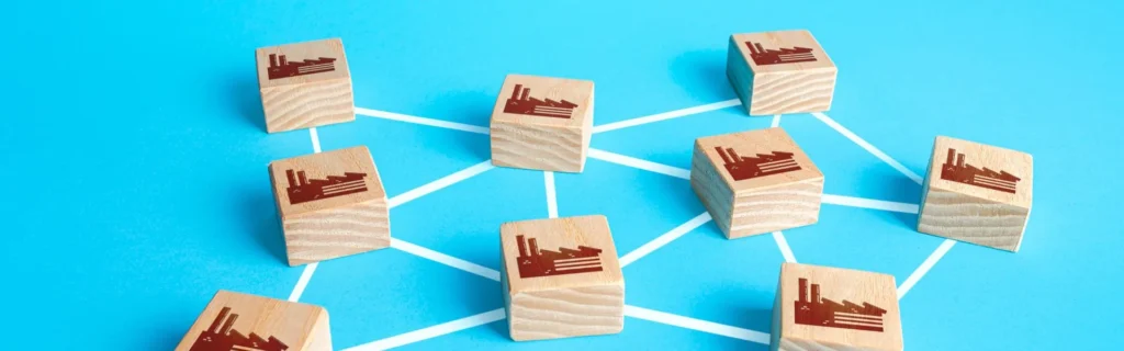 Representació visual d'una xarxa d'empreses B2B connectades mitjançant blocs de fusta amb icones de fàbriques sobre un fons blau.