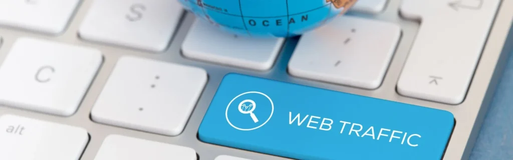 Tecla azul de tráfico web y globo terráqueo sobre un teclado, metáfora de la analítica y el tráfico orgánico internacional.
