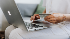 Primer plano de una persona utilitzando una tarjeta de credito para hacer una compra en un ordinador portatil