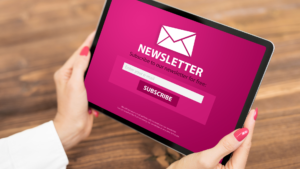 Una persona sostenint una tauleta que mostra un formulari de subscripció a una newsletter amb el fons fúcsia.