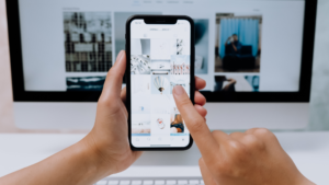 Primer pla d'una persona revisant un feed d'Instagram organitzat i estètic en un telèfon mòbil en un entorn d'oficina.