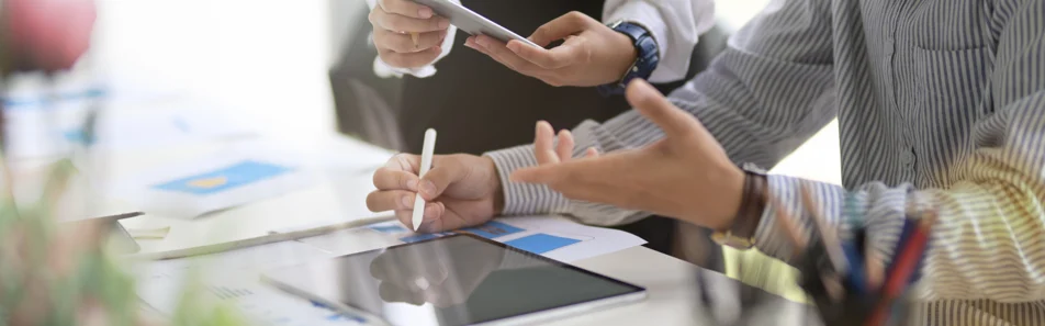 Equip de treball analitzant les millors estratègies de màrqueting B2B en una tauleta i documents sobre un escriptori