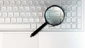 Lupa sobre un teclado de computadora, metáfora de la investigación de palabras clave en marketing digital.